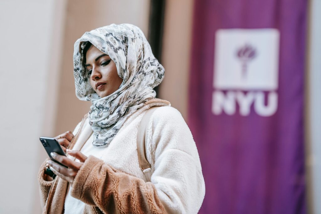 A female student pressing her phone while waiting for her friends