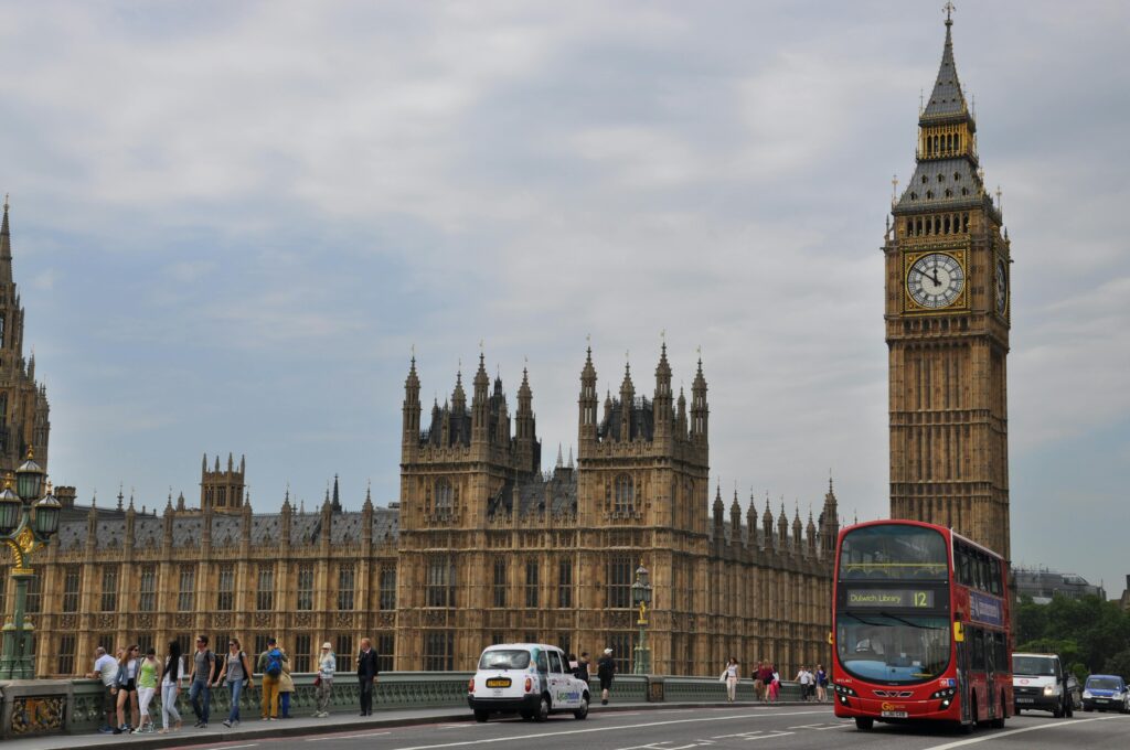 People and Vehicles Traveling on the Road near the Famous Palace of Westminster