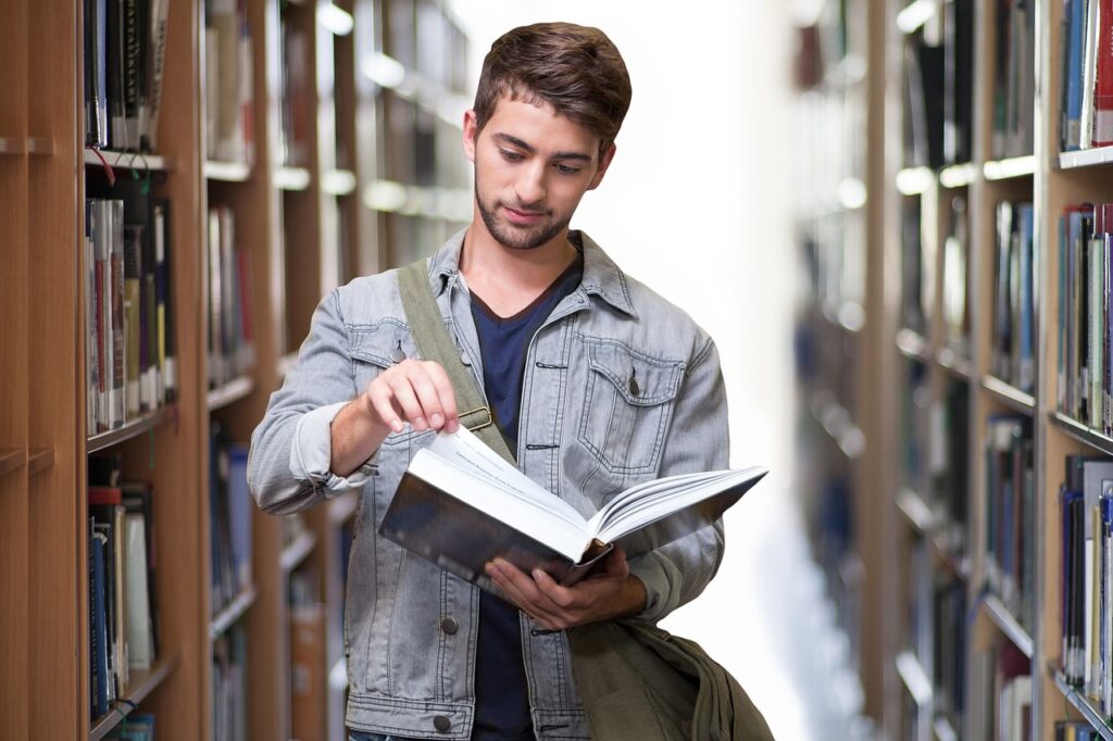 A male College student picking a book in the library