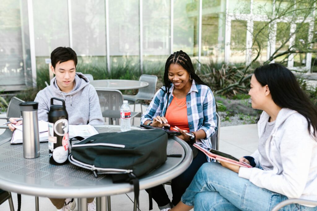 One male and two female students sitting together outside the classroom studying