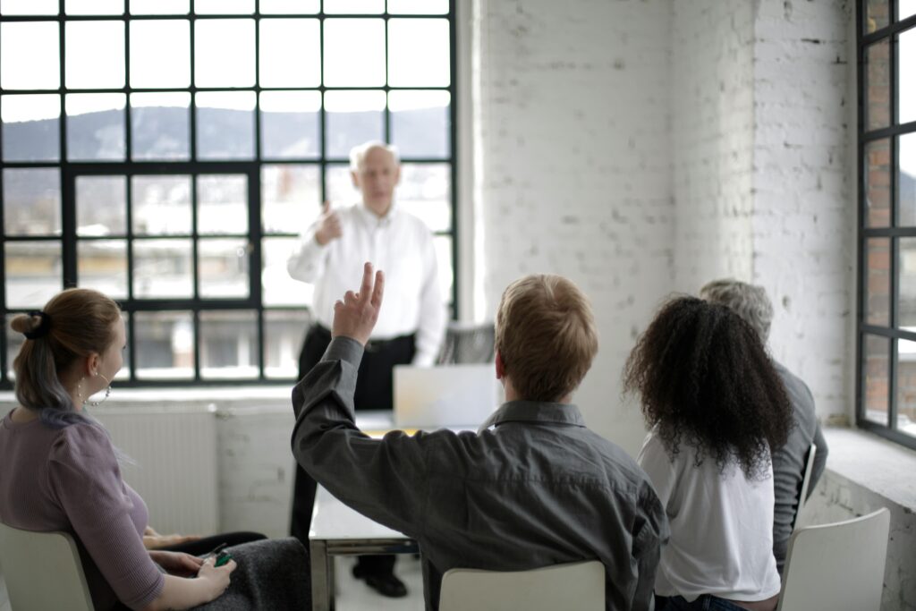 College Students and their teacher Having a Discussion in a White Room