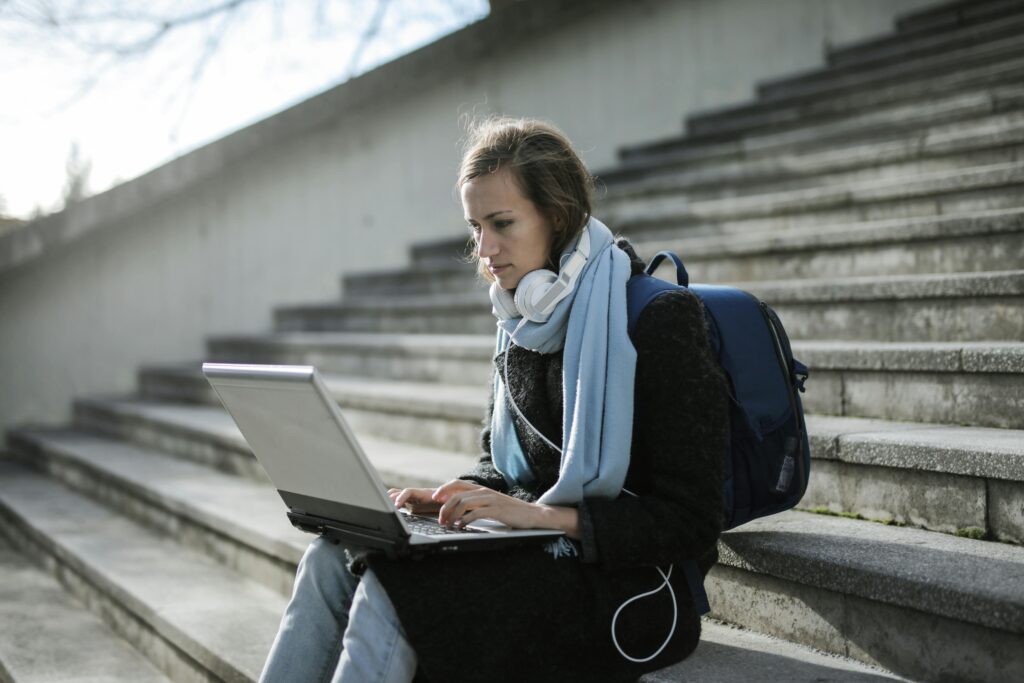 A female student Sitting On Concrete Stairs Using Laptop