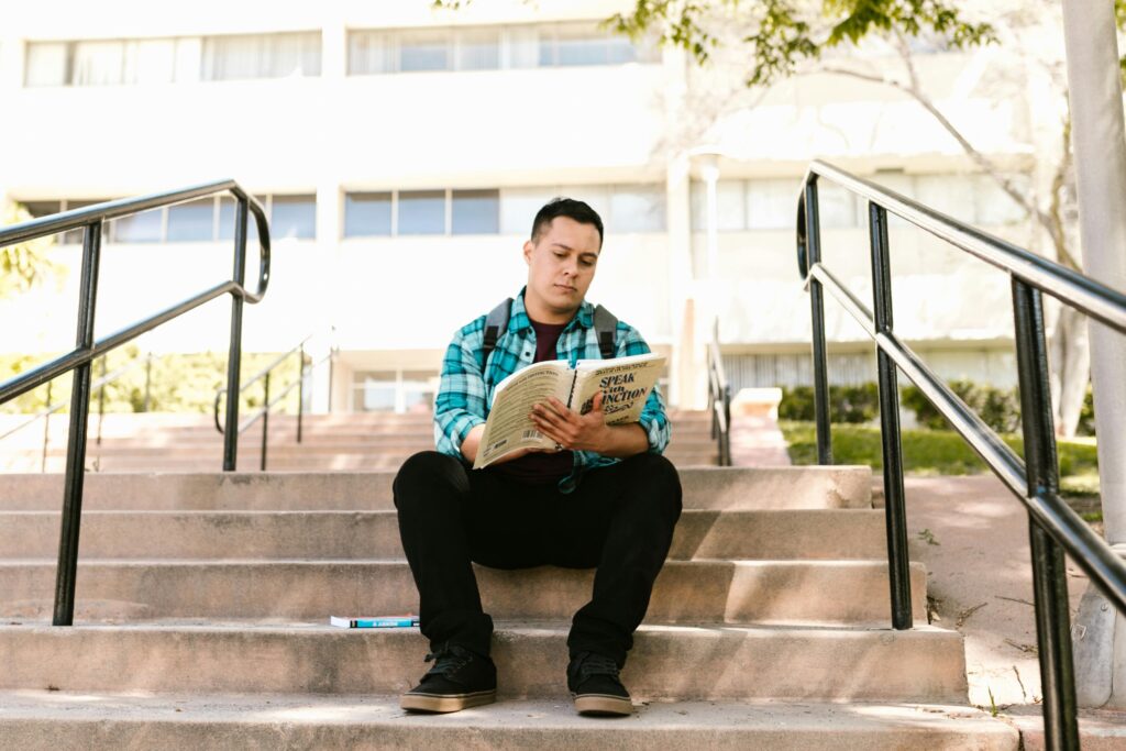 Man in Blue White and Brown Plaid Dress Shirt and Black Pants Sitting on Concrete Stairs