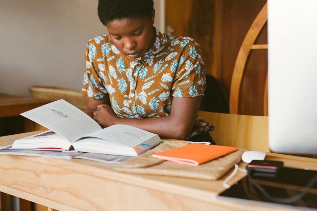 A female student reading her book with her phone placed on the table