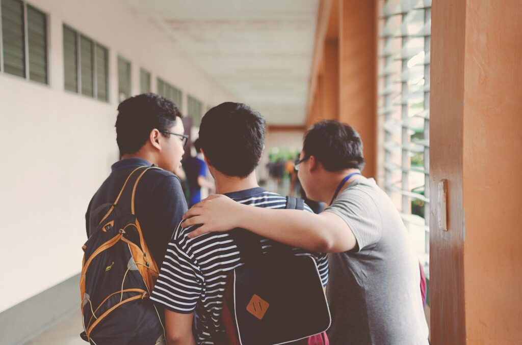 Three college students walking through the hallway with their bags